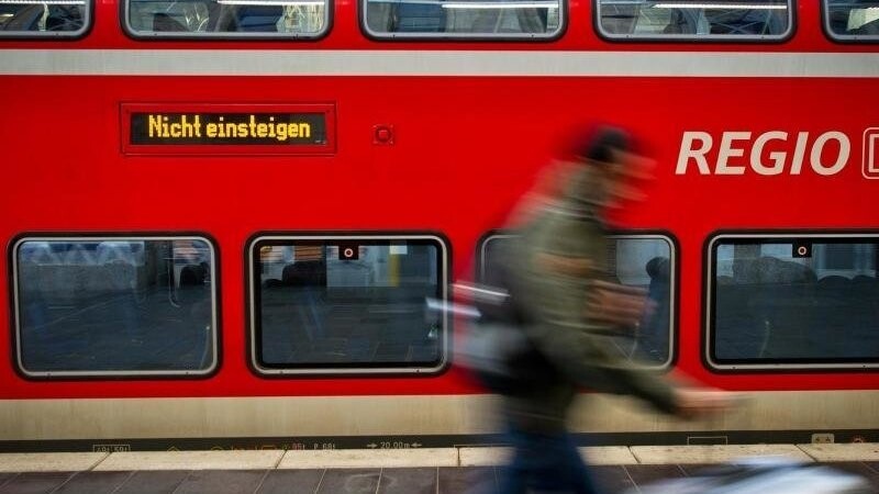 Ein Fahrgast läuft in einem Hauptbahnhof an einer Regionalbahn der Deutschen Bahn vorbei. Foto: Christoph Schmidt/dpa/Archivbild