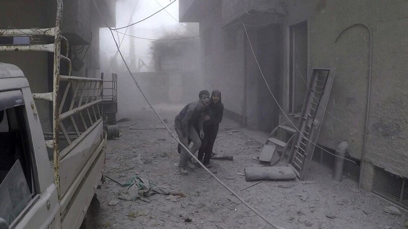 Das vom Syrischen Zivilschutz (Weißhelme) bereitgestellte Foto zeigt zwei Zivilisten, die nach einem Luftangriff in einem von Rebellen kontrollierten Vorort von Damaskus flüchten.