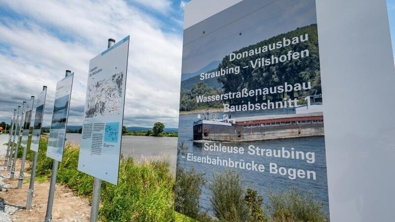 Ein Schild mit der Aufschrift "Donauausbau - Straubing-Vilshofen" steht am Ufer der Donau.
