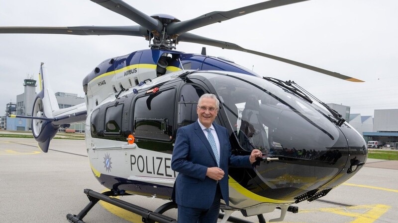 Bayerns Innenminister Joachim Herrmann steht neben einem neuen Hubschrauber der bayerischen Polizei.