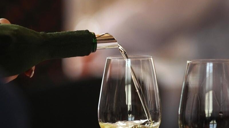 Aus einem verdeckten Bocksbeutel wird fränkischer Weißwein eingeschenkt.