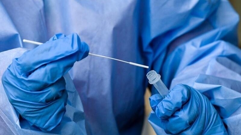 Eine Krankenschwester steckt ein Abstrichstäbchen in die Flüssigkeit eines Corona-Schnelltests.