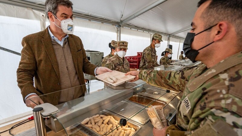 Markus Söder (CSU), Ministerpräsident von Bayern, reicht einem US-Soldaten ein Weißwurstfrühstück.