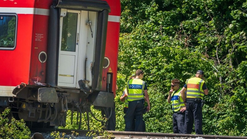 Polizisten stehen hinter dem verunfallten Regionalzug, der noch an der Unfallstelle steht.