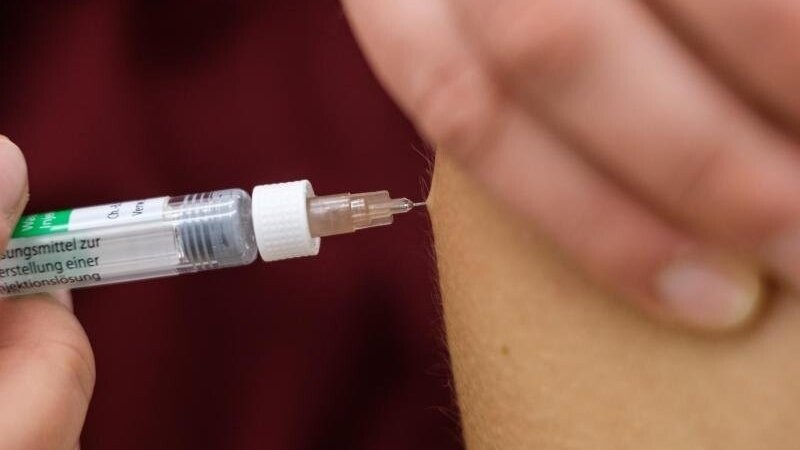 Eine Arzthelferin impft eine Patentin mit einer Spritze.