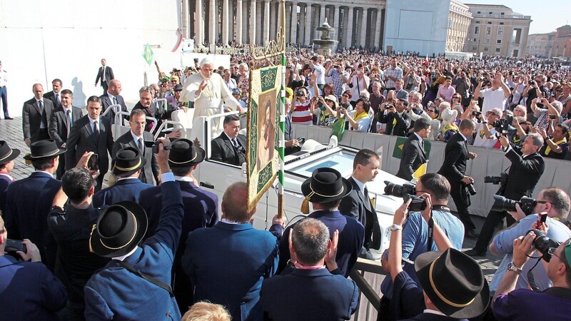 Begegnung mit dem bayerischen Papst im Oktober 2012: Benedikt XVI. fährt durch die Reihen am Petersplatz. Im Vordergrund ein Teil der Pfingstreiter, die mit den Symbolen des Pfingstritts an der Generalaudienz teilnahmen.