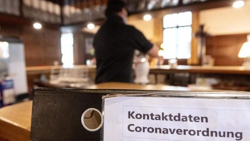 Ein Ordner mit der Aufschrift "Kontaktdaten Coronaverordnung" liegt in einer Gaststätte auf der Theke.