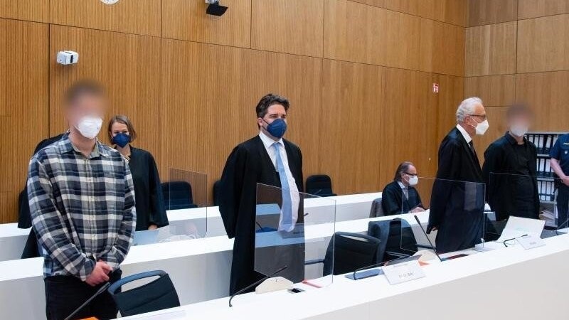 Die zwei wegen Mordes angeklagten Männer (l und 2.v.r.) stehen vor Beginn der Verhandlung mit ihren Anwälten im Sitzungssaal.