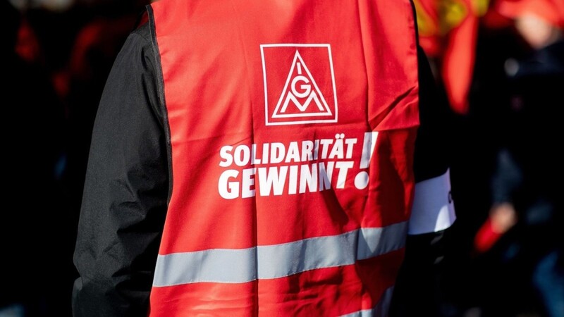 Ein Teilnehmer einer Kundgebung der IG Metall trägt eine rote Weste mit der Aufschrift "Solidarität gewinnt!".