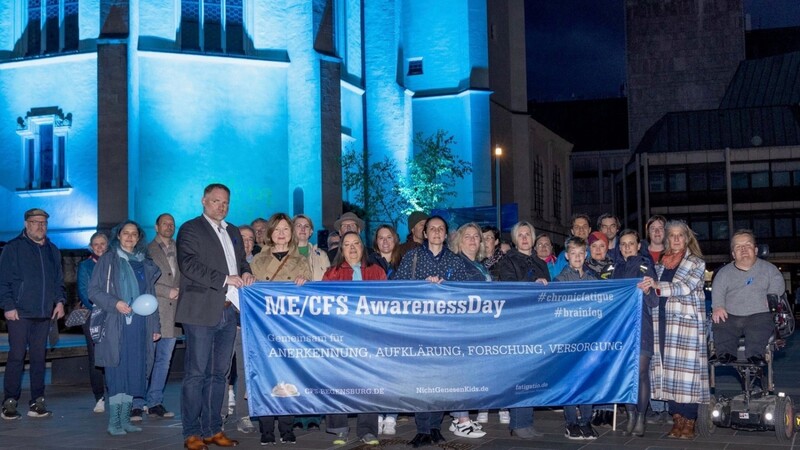 Betroffene, Unterstützer und Politiker kamen zum ME/CFS-Awareness-Day 2023 am Neupfarrplatz zuammen. Die Neupfarrkirche leuchtete dazu blau.