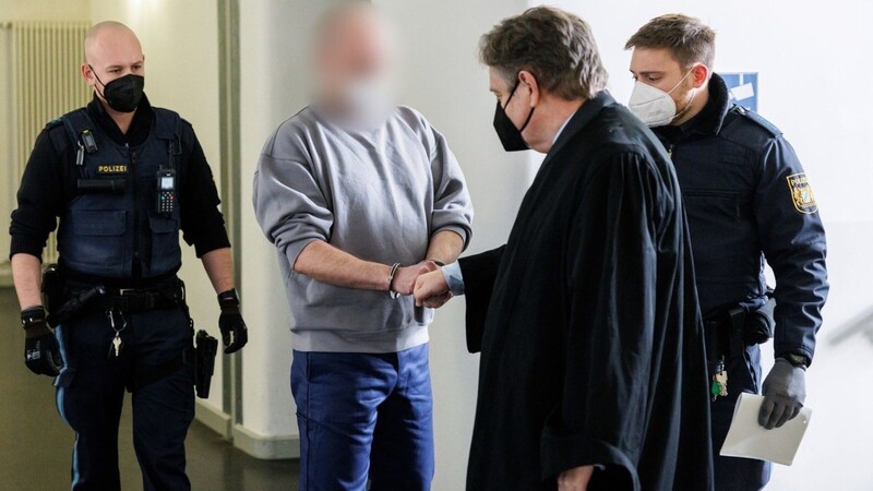 Der Angeklagte (2.v.l) begrüßt im Landgericht seinen Rechtsanwalt Andreas Kaiser.