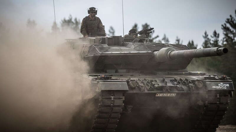 Ein Leopard-2-Panzer der Bundeswehr fährt beim Besuch von Bundeskanzler Scholz durch das Camp Adrian Rohn.