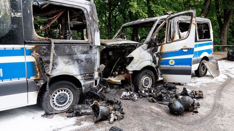 Polizeiautos die in der Nacht gebrannt hatten, stehen am Morgen zwischen anderen Einsatzfahrzeugen.