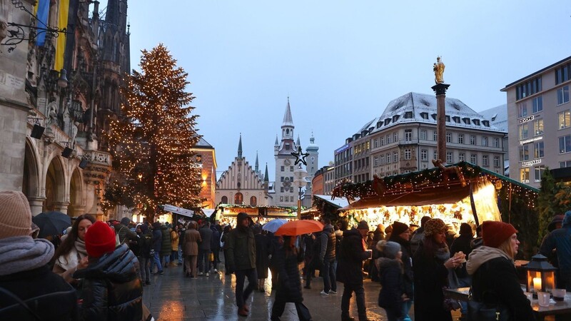 Menschen gehen über den festlich geschmückten Christkindlmarkt auf dem Marienplatz.