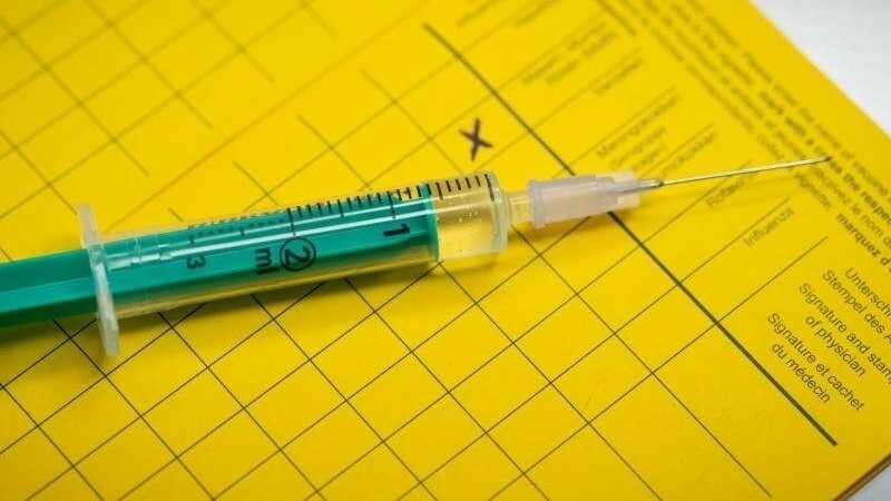 Eine Spritze liegt auf einem Impfpass.