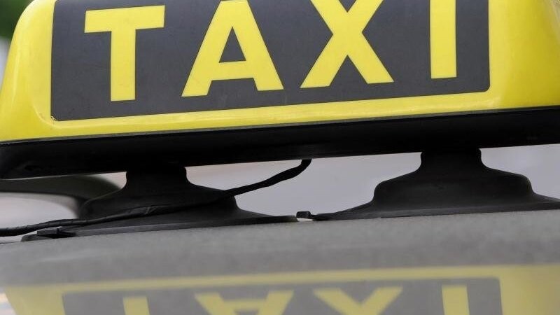 Ein Taxischild spiegelt sich in einem Autodach. Foto: Franziska Kraufmann/Archiv