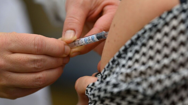 Ein Arzt impft eine Frau gegen die Grippe.