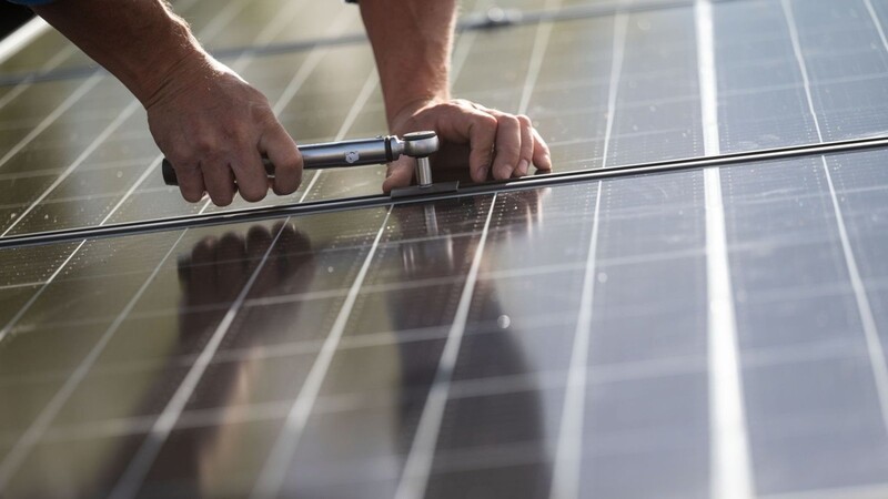 Ein Mann montiert Photovoltaikmodule auf einem Dach.