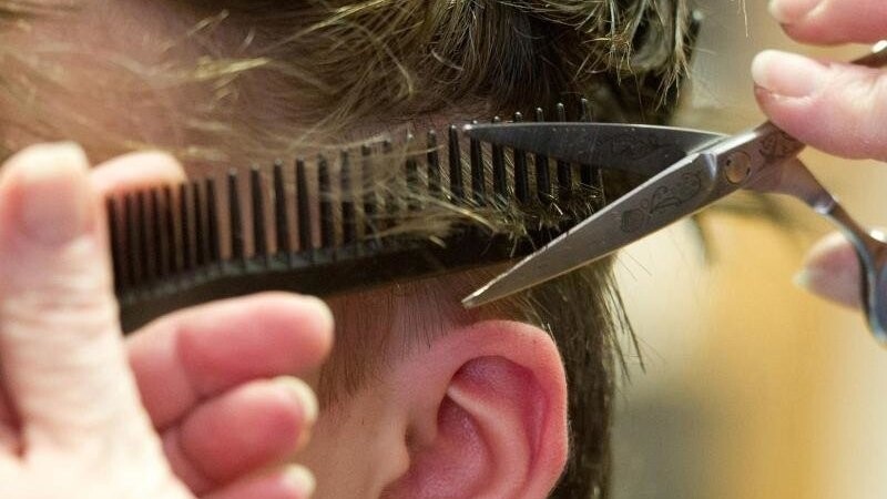 Eine Friseurin schneidet die Haare einer Kundin. Foto: Sebastian Kahnert/dpa/Archivbild