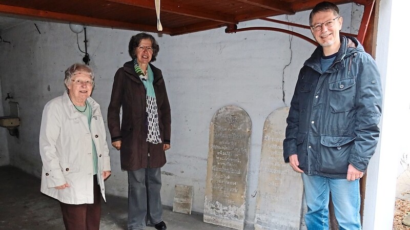 Museumshistoriker Max Tewes mit Besitzerin Wilhelmine Schmitt und deren Tochter in der Garage mit den gefundenen Grabsteinen.