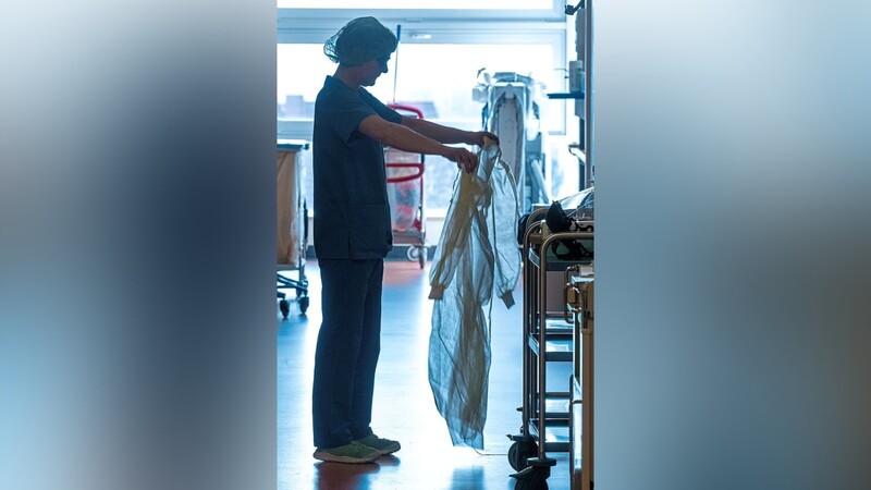 Eine Krankenschwester legt Schutzkleidung an, bevor sie ein Patientenzimmer betritt.