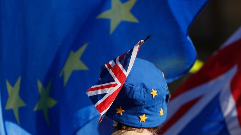 Ein Pro-Europäischer Demonstrant blickt auf wehende Flaggen der Europäischen Union und Großbritanniens und trägt einen Hut in EU-Farben an dem eine britische Flagge befestigt ist. Das Gesetz gegen den No-Deal-Brexit ist am Montag den 09.09.2019 in Kraft getreten.