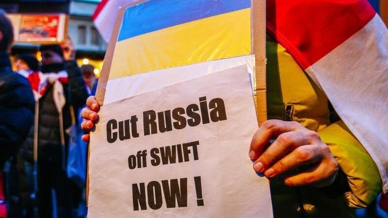 Ein Demonstrant hält ein Schild mit der ukrainischen Flagge und der Aufschrift "Russland jetzt abschneiden!".