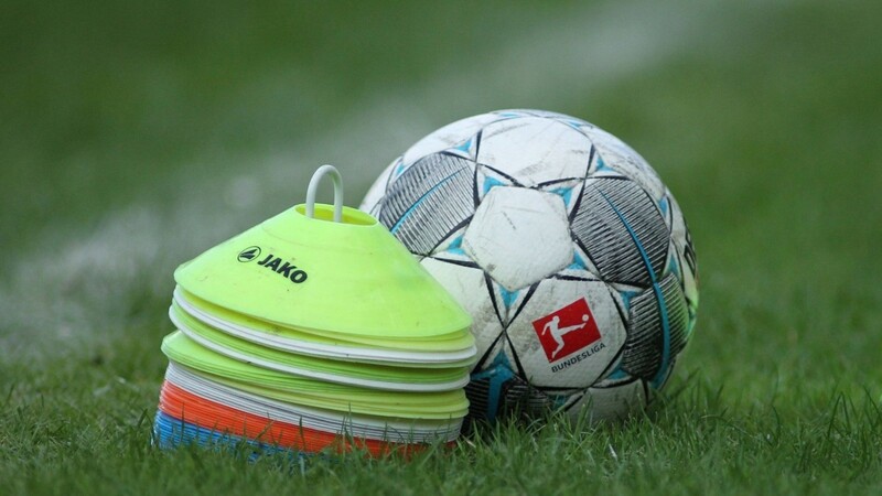 Ein Fußball liegt neben Hütchen auf dem Rasen (Symbolbild).