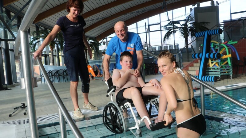 Schwimmtrainerin Uschi Radius (l.), Pestalozzi-Konrektor Hans Englert und Rettungsschwimmerin Jeanette Pylinski (r.) helfen dem 12-jährigen Lino ins Wasser.