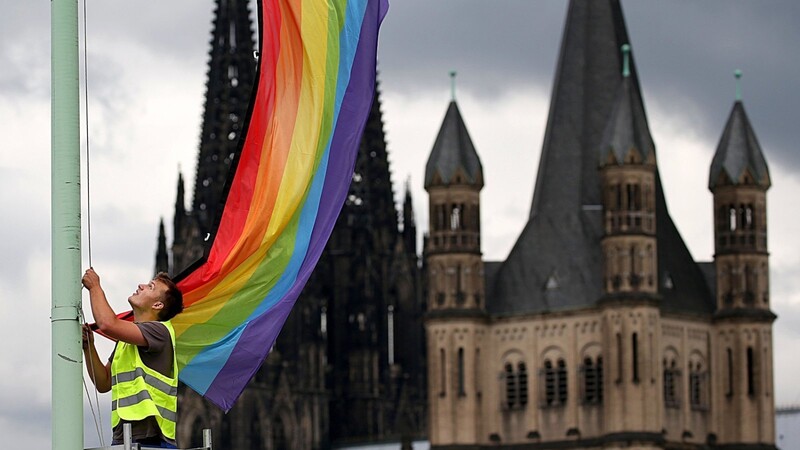Vor der Kulisse des Kölner Doms hängt 2017 ein Arbeiter nach der Entscheidung im Bundestag über die "Ehe für alle" eine Regenbogenfahne auf.