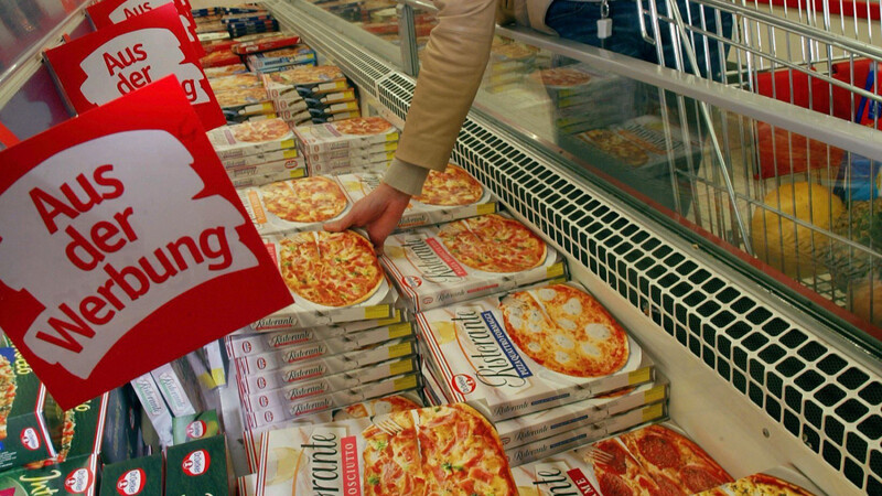 Eine junge Frau schaut in einem Supermarkt nach Fertiggerichten und Tiefkühlpizza. (Symbolbild)