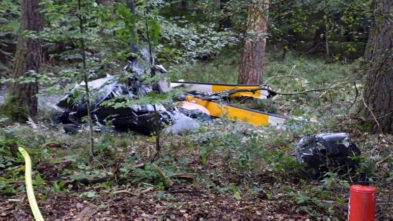 Trümmerteile eines Hubschraubers vom Typ Robinson R44 und ein Schlauch der Feuerwehr liegen in einem Wald nahe der Grenze zu Hessen und Bayern.