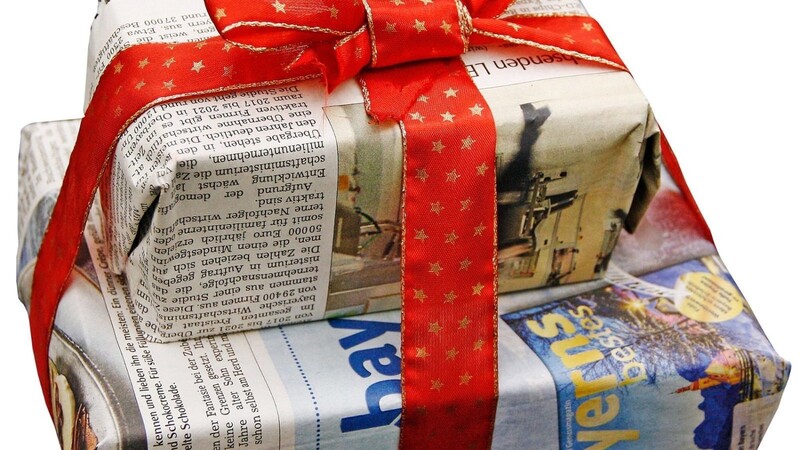 Verpackung aus Zeitungspapier mit einem aufbewahrten Geschenkband aus dem Vorjahr.