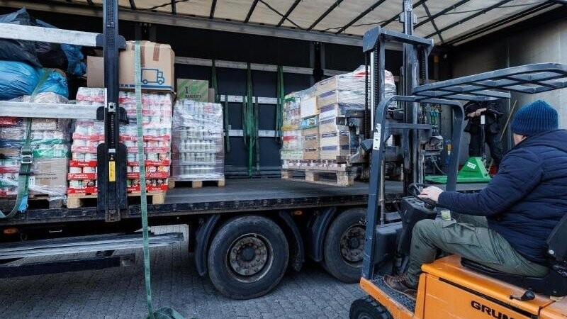 Ein Helfer lädt eine Europalette auf einen Lastwagen.