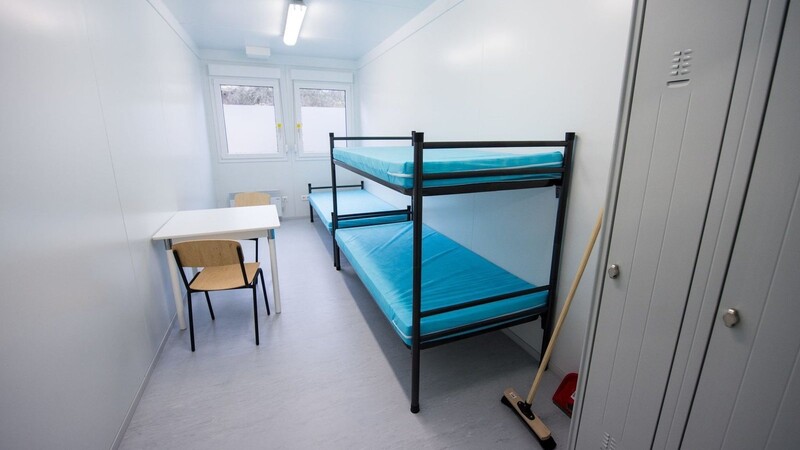 Blick in ein Zimmer mit drei Betten in einem Wohncontainer in einer Erstaufnahmeunterkunft.
