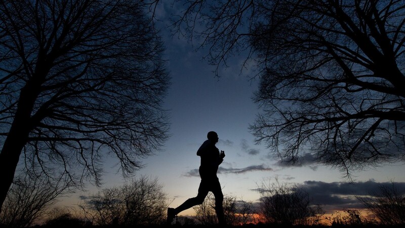 Ein Mann joggt am Abend bei Sonnenuntergang.