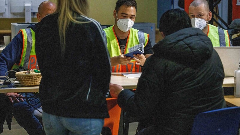 Ein Polizist kontrolliert den Reisepass einer Geflüchteten im Ukraine-Ankunftszentrum Tegel, Terminal C, im ehemaligen Flughafen Tegel. Die Kommunen warnen die Bundesregierung vor Überforderung.