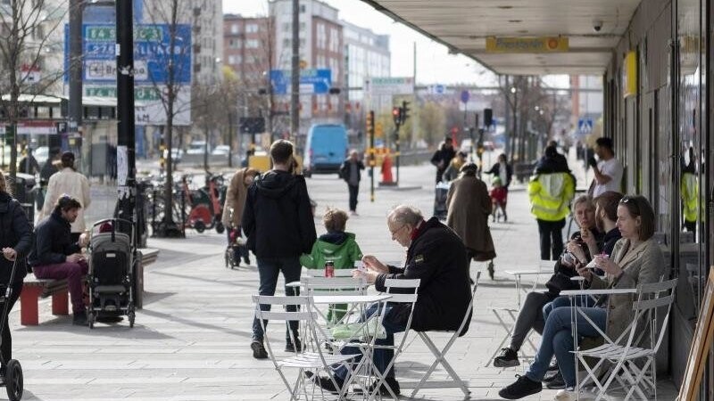 Menschen sitzen im Stadtzentrum von Stockholm vor einem Eiscafe.