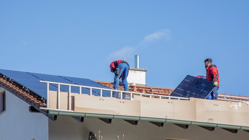 Bauarbeiter montieren auf einem Privathaus Solaranlagen. Nach dem Willen der Stadt sollen auch städtische Gebäude mehr Photovoltaik bekommen.