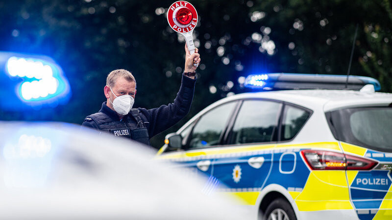 Ein Polizeibeamter steht bei einer Corona-Einreisekontrolle der Bundespolizei an der deutsch-niederländischen Grenze mit einem Polizeianhaltestab und kontrolliert Fahrzeuge im Grenzgebiet. Für Rückkehrer aus dem Sommerurlaub greifen ab Sonntag strengere Testpflichten zum Schutz vor einer Corona-Ausbreitung.