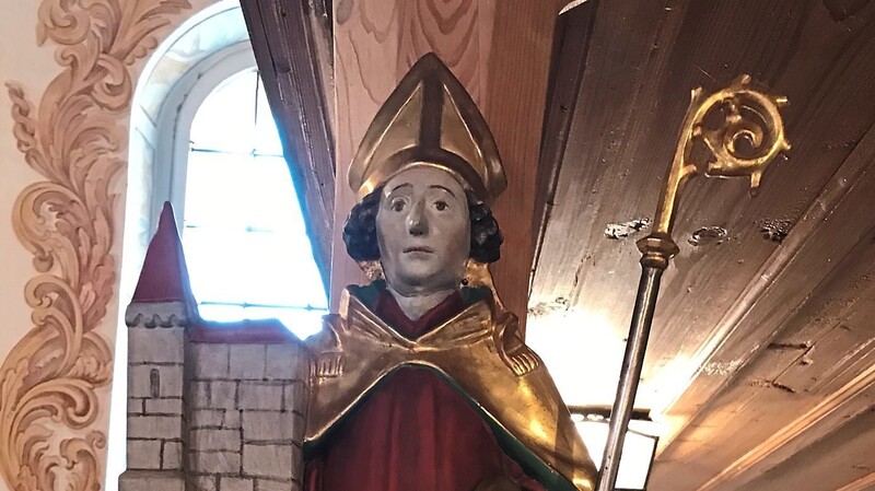 Eine Figur des Heiligen Wolfgang am Eingang der Kirche heißt alle Gläubigen willkommen.