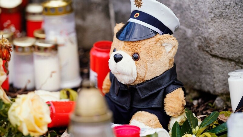 Kerzen, Blumen und ein Teddybär in Polizeiuniform liegen auf dem Vorplatz der Kirche St. Remigius. Zwei Wochen nach den Todesschüssen auf zwei Polizisten in der Westpfalz wird der 29 Jahre alte Polizeikommissar am Dienstag in seinem Heimatort Freisen im Saarland beigesetzt.