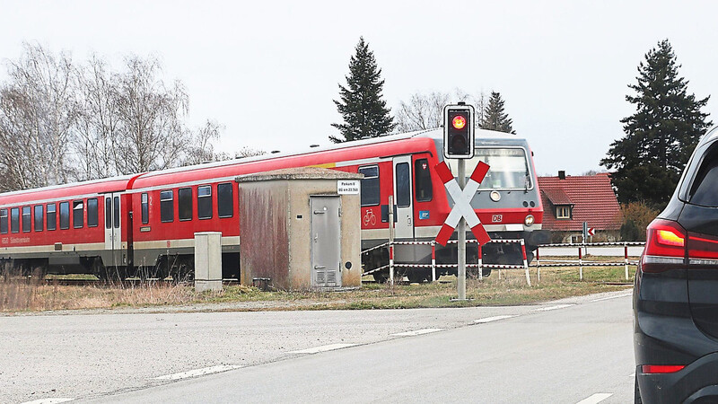 Ein Autofahrer wartet am höhengleichen Bahnübergang in Perkam an der roten Ampel, während ein Zug durchfährt. Der Übergang ist einer von vieren, bei dem derzeit über eine Neugestaltung nachgedacht wird.