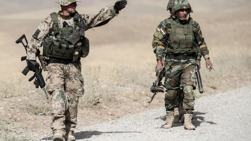 Bundeswehrsoldaten und kurdische Peshmerga gehen bei einer Übung.