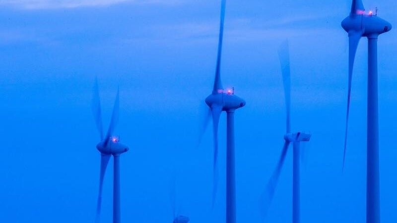 Windkraftanlagen drehen sich vor Sonnenaufgang in einem Windpark bei Kladrum.