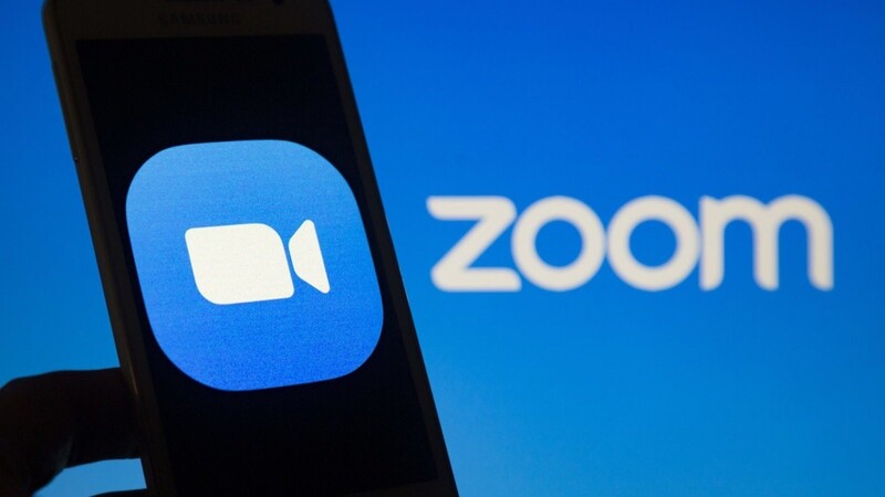 Das Logo vom Videokonferenz-Dienst Zoom ist auf einem Smartphone-Bildschirm zu sehen. Mit virtuellen Hintergründen kann man in der Videokonferenz punkten.