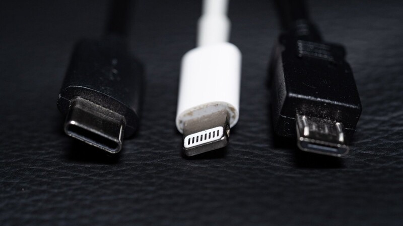 Ein USB-C (l-r), ein Apple Lightning und ein Micro-USB Kabel (l-r) liegen nebeneinander.