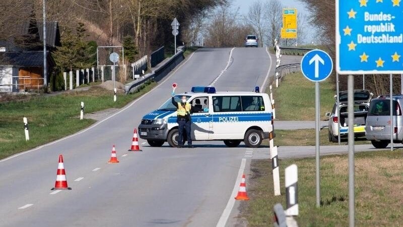 Polizisten stehen an der Bundesstraße 512 an einer Kontrollstelle an der Grenze zu Österreich. Foto: Sven Hoppe/dpa/Archivbild