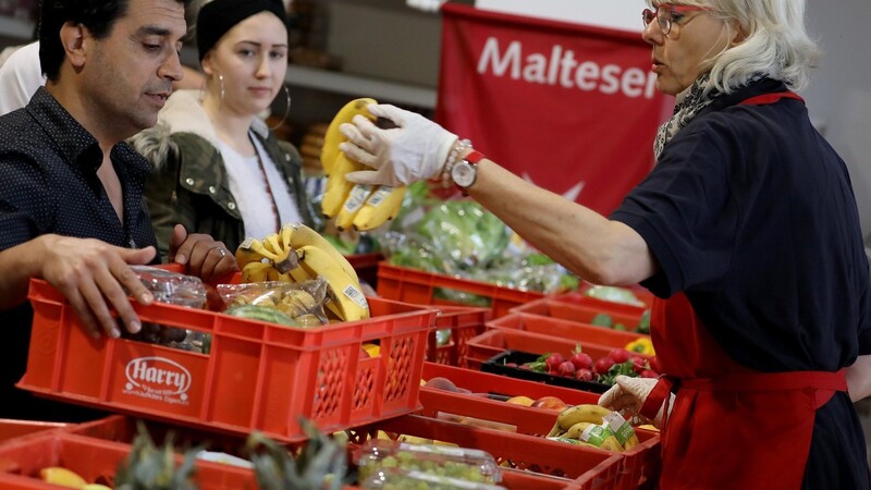 Mitarbeiter der Hilfsorganisation der Malteser verteilen in der Tafel Lebensmittel.