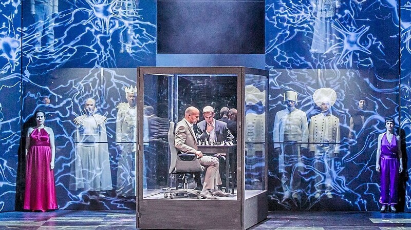 Starke Bühnenausstattung: Die Schachspieler sitzen beim Wettkampf isoliert im Glaskasten. Der Chor tritt als Schachfiguren auf.